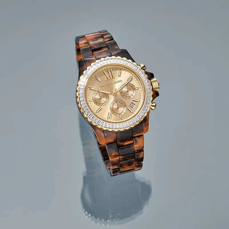 Reloj Mkors analogo, para Dama, tablero redondo color dorado, estilo index + romano, pulso plastico color café, calendario, cronografo