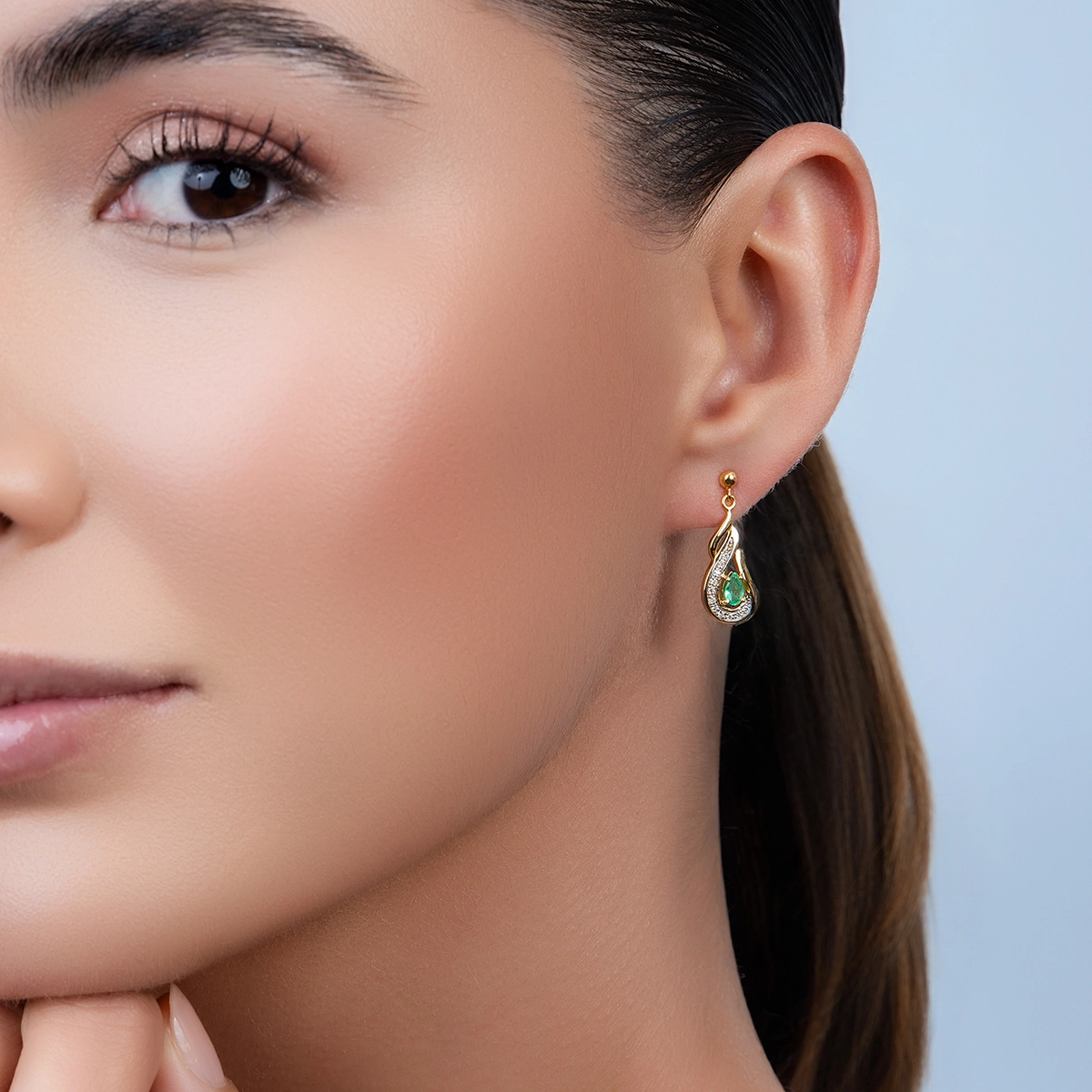 Aretes en oro amarillo de 18 Kilates, Onda, con 2 esmeraldas centrales de 0.40 Ct y decoración en diamantes de 0.11 Ct
