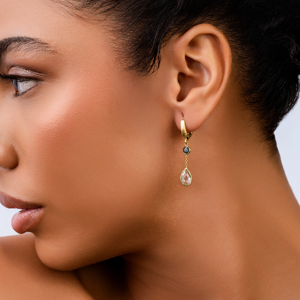 Aretes en oro amarillo de 18 Kilates satinado, Bisel+decoración, con 2 topacios centrales y decoración en zircones
