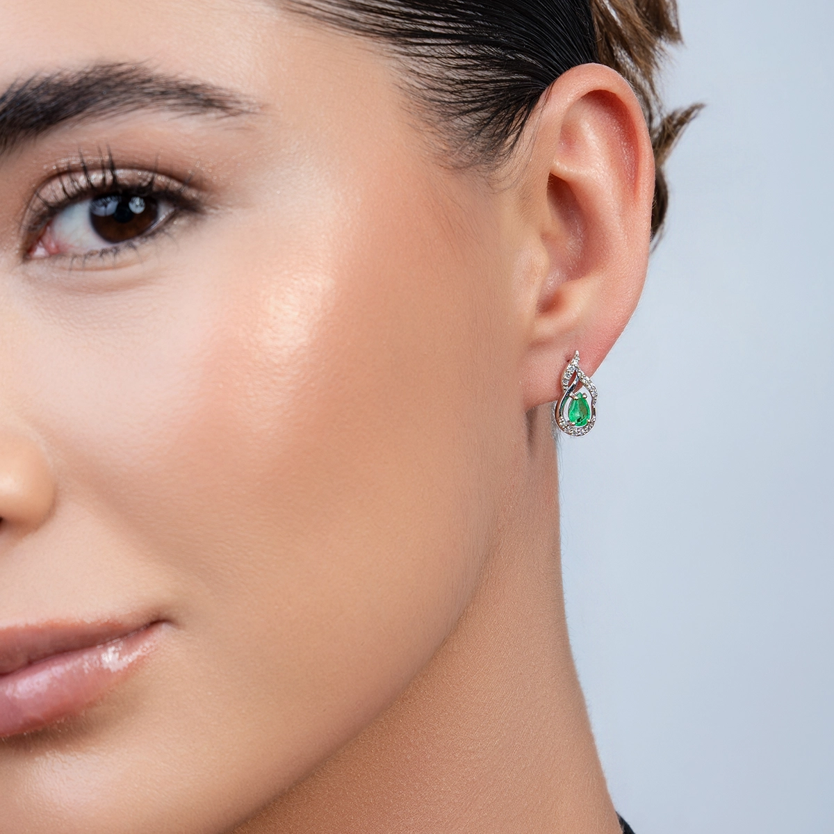 Aretes en oro blanco de 18 Kilates, Onda, con 2 esmeraldas centrales de 0.75 Ct y decoración en diamantes de 0.18 Ct