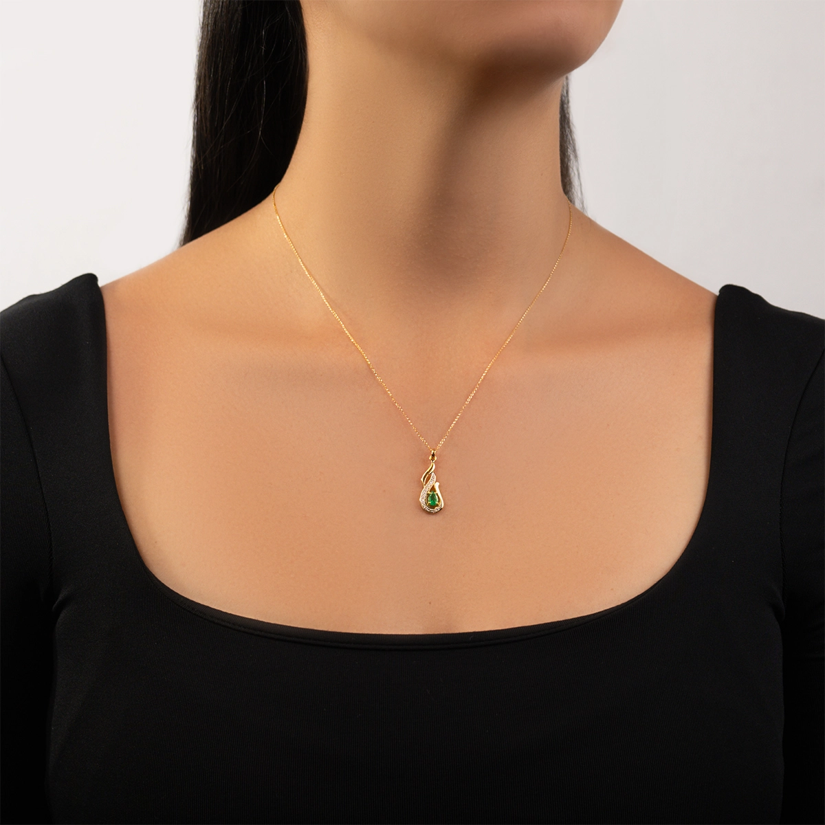 Dije en oro amarillo de 18 Kilates, Onda, con esmeralda central de 0.40 Ct y decoración en diamantes de 0.07 Ct