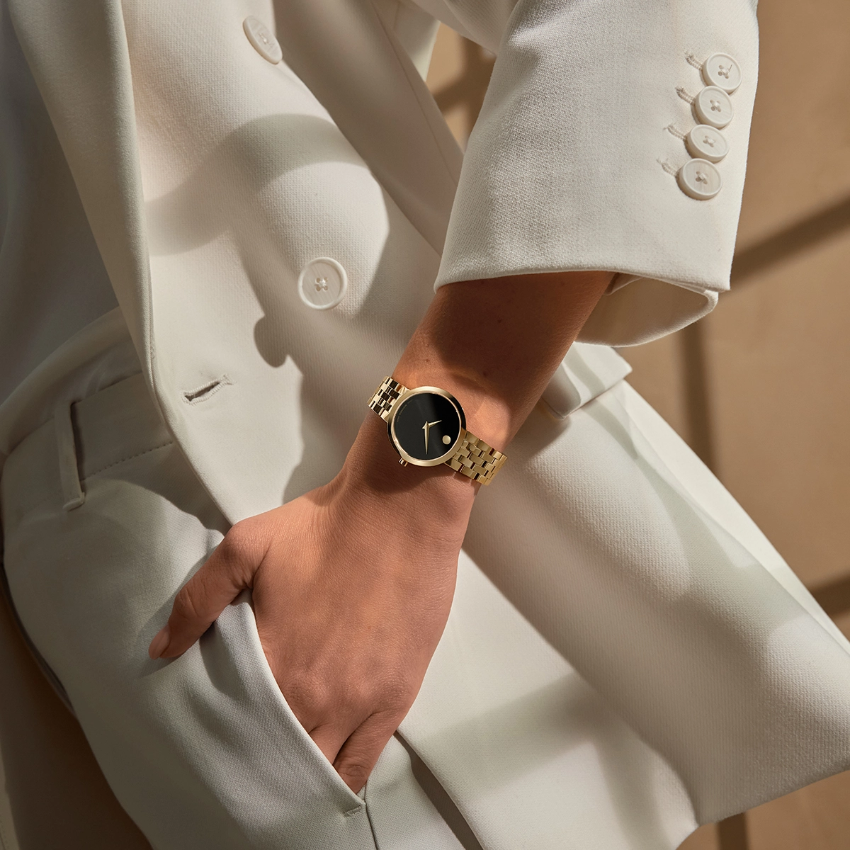 Mujer de traje blanco luciendo un Movado Museum Classic dorado